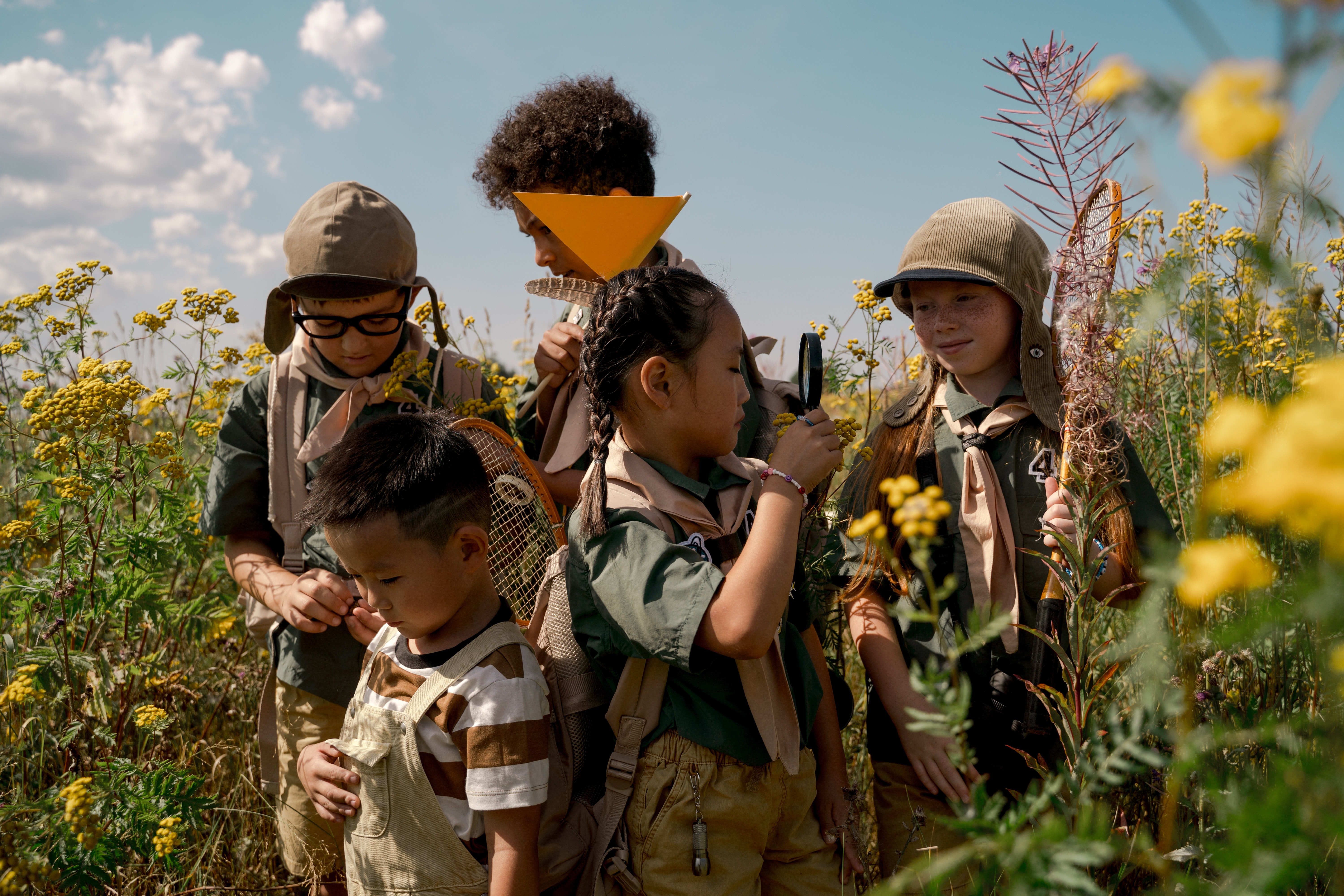 5 scouts children in uniform searching a field